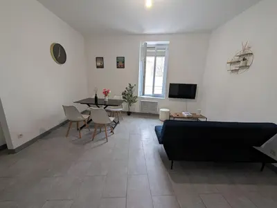 a living room with a couch and a table and chairs at Agréable appartement 65 m2 type 3 Narbonne centre-ville in Narbonne