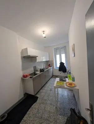 a kitchen with white cabinets and a table in it at Agréable appartement 65 m2 type 3 Narbonne centre-ville in Narbonne