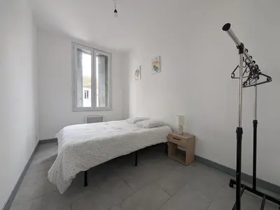 a white bedroom with a bed and a window at Agréable appartement 65 m2 type 3 Narbonne centre-ville in Narbonne
