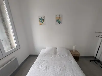a white bed in a room with a window at Agréable appartement 65 m2 type 3 Narbonne centre-ville in Narbonne