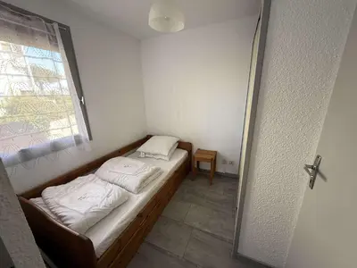 a small bed in a room with a window at AIG 52 – Appartement en rez-de-chaussée – Résidence de la Plage – Gruissan – 4 personnes in Gruissan