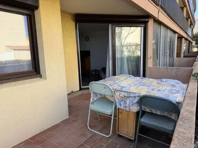 a table and chairs sitting on a patio at AIG 52 – Appartement en rez-de-chaussée – Résidence de la Plage – Gruissan – 4 personnes in Gruissan