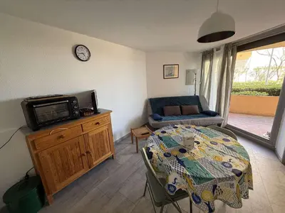 a living room with a table and a tv on a cabinet at AIG 52 – Appartement en rez-de-chaussée – Résidence de la Plage – Gruissan – 4 personnes in Gruissan