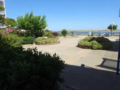 a park with a bench next to the beach at AIG 52 – Appartement en rez-de-chaussée – Résidence de la Plage – Gruissan – 4 personnes in Gruissan