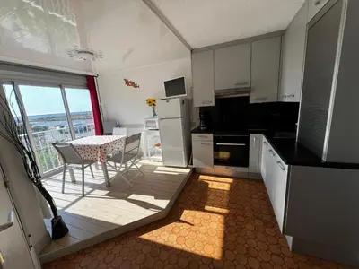 a kitchen with white cabinets and a table with a view at AIG 59 – Studio avec 2 cabines – Résidence Grand Sud – Gruissan – 4 personnes in Gruissan