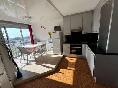 a kitchen with white cabinets and a table with a view at AIG 59 – Studio avec 2 cabines – Résidence Grand Sud – Gruissan – 4 personnes in Gruissan
