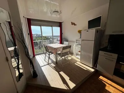 a small kitchen with a table and a refrigerator at AIG 59 – Studio avec 2 cabines – Résidence Grand Sud – Gruissan – 4 personnes in Gruissan