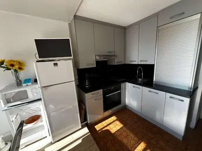 a kitchen with white cabinets and a white refrigerator at AIG 59 – Studio avec 2 cabines – Résidence Grand Sud – Gruissan – 4 personnes in Gruissan