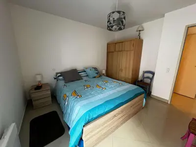 a bedroom with a bed with blue sheets and bananas on it at AIG 84 – Appartement T3 – Résidence Ephyra – Gruissan – 4 personnes in Gruissan
