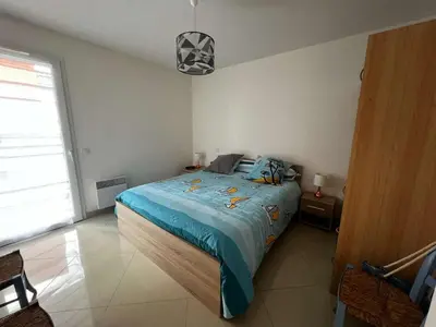 a bedroom with a bed with a blue comforter at AIG 84 – Appartement T3 – Résidence Ephyra – Gruissan – 4 personnes in Gruissan