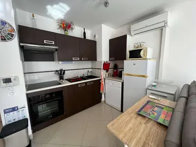 a kitchen with brown cabinets and a white refrigerator at AIG 84 – Appartement T3 – Résidence Ephyra – Gruissan – 4 personnes in Gruissan