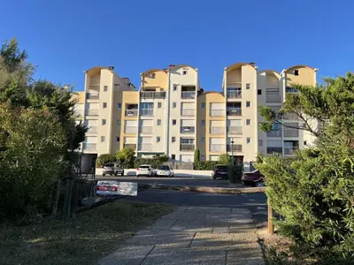 a large building with cars parked in a parking lot at AIG_183 Studio rénové avec terrasse et vue exceptionnelle sur la marina, l’étang et le village de Gruissan in Gruissan