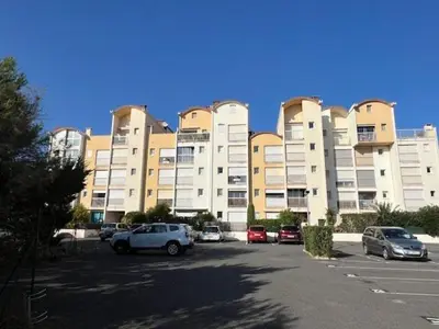 a large building with cars parked in a parking lot at AIG_183 Studio rénové avec terrasse et vue exceptionnelle sur la marina, l’étang et le village de Gruissan in Gruissan