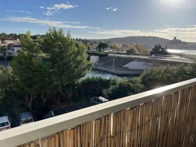 a view of a river and a bridge with cars at AIG_183 Studio rénové avec terrasse et vue exceptionnelle sur la marina, l’étang et le village de Gruissan in Gruissan
