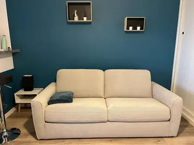 a white couch in a living room with a blue wall at AIG_183 Studio rénové avec terrasse et vue exceptionnelle sur la marina, l’étang et le village de Gruissan in Gruissan