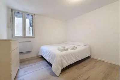 a white bedroom with a bed and a window at Le Garibaldi - Appartement proche du centre - Wi-Fi in Narbonne