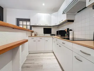 a white kitchen with white cabinets and a counter at Le Garibaldi - Appartement proche du centre - Wi-Fi in Narbonne
