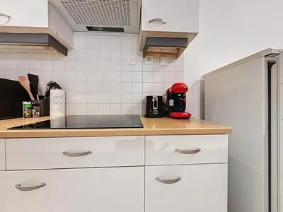 a kitchen with white cabinets and a red appliance at Le Garibaldi - Appartement proche du centre - Wi-Fi in Narbonne
