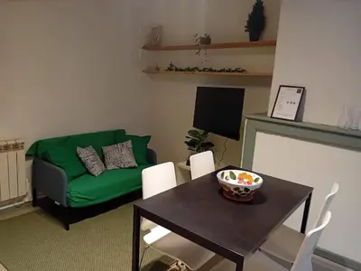 a living room with a table and a green couch at Le Damier in Quillan