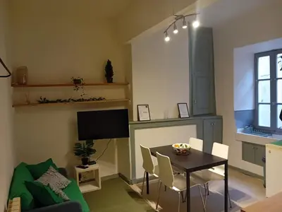 a living room with a table and chairs and a television at Le Damier in Quillan