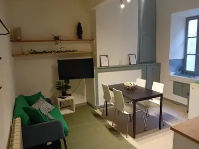 a living room with a table and chairs and a television at Le Damier in Quillan