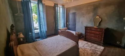 a bedroom with a bed and a dresser and windows at La Maison Jolie bnb in Puicheric