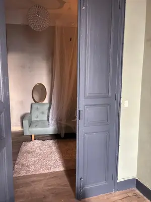a room with a blue door and a chair at La Maison Jolie bnb in Puicheric