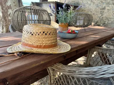 a straw hat is sitting on a wooden table at La Maison Jolie bnb in Puicheric
