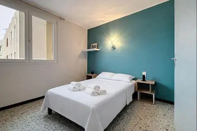 a bedroom with a large white bed with a blue wall at Le Cassayet - Appartement proche des Grands Buffets - Wifi et Climatisation in Narbonne