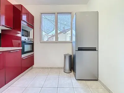 a kitchen with a stainless steel refrigerator and red cabinets at Le Cassayet - Appartement proche des Grands Buffets - Wifi et Climatisation in Narbonne