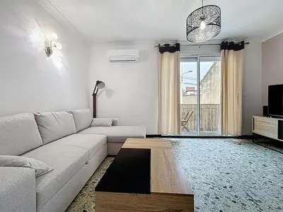 a living room with a white couch and a tv at Le Cassayet - Appartement proche des Grands Buffets - Wifi et Climatisation in Narbonne