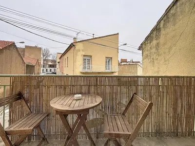 a wooden table and two chairs sitting on a balcony at Le Cassayet - Appartement proche des Grands Buffets - Wifi et Climatisation in Narbonne
