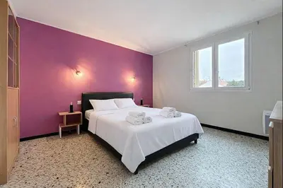 a bedroom with a large bed with a purple wall at Le Cassayet - Appartement proche des Grands Buffets - Wifi et Climatisation in Narbonne