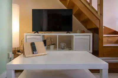 a living room with a white table and a tv at Duplex cosy à Mirepoix centre, tout confort in Mirepoix