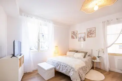a white bedroom with a bed and a tv at Duplex cosy à Mirepoix centre, tout confort in Mirepoix