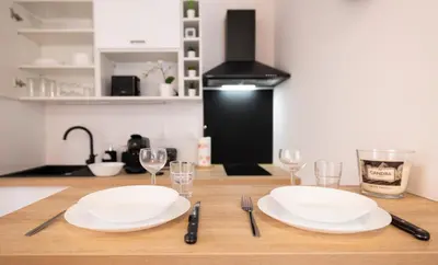 a table with two white plates and glasses on it at Duplex cosy à Mirepoix centre, tout confort in Mirepoix