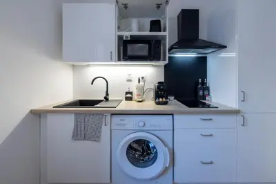 a kitchen with a sink and a washing machine at 2 appartements cosys en plein cœur de Varilhes in Varilhes