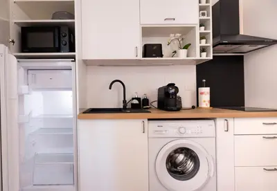 a kitchen with a washing machine and a microwave at 2 appartements cosys en plein cœur de Varilhes in Varilhes