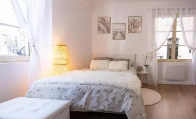 a white bedroom with a bed and a window at 2 appartements cosys en plein cœur de Varilhes in Varilhes