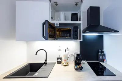 a kitchen with a sink and a microwave at 2 appartements cosys en plein cœur de Varilhes in Varilhes