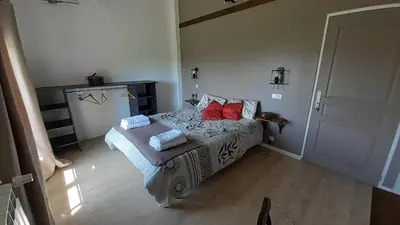 a bedroom with a bed with red pillows on it at Les chambres de Guillaunas Haut in Saint-Germain-des-Prés