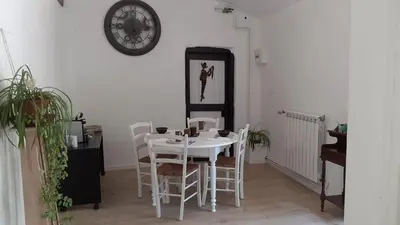 a white table and chairs in a room with a clock at Les chambres de Guillaunas Haut in Saint-Germain-des-Prés