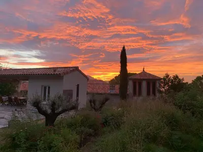 a sunset over a house and a tree in a yard at Domaine de Grave in Mirepoix