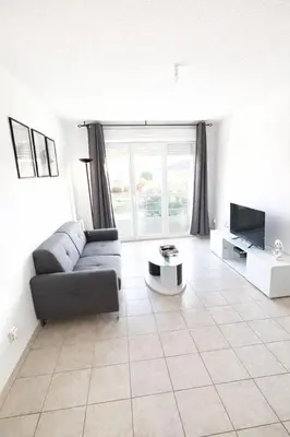 a living room with a couch and a tv at T2 lumineux avec parking privé in Narbonne