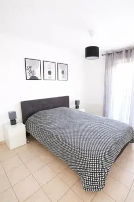 a bedroom with a bed with a black and white bedspread at T2 lumineux avec parking privé in Narbonne