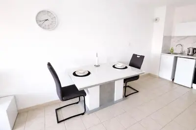 a white table and chairs in a kitchen with a clock at T2 lumineux avec parking privé in Narbonne