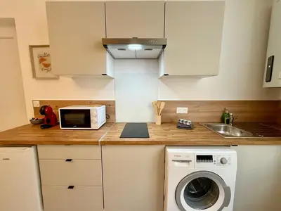a kitchen with a washing machine and a microwave at L'Atrium - Cour intérieure & box vélo, rdc in Castelnaudary