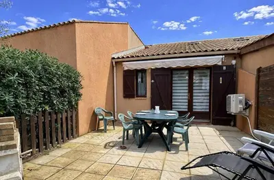 a patio with a table and chairs and a fence at Pavillon avec grande terrasse à l'abri des regard, piscine, clim - GN020-008 in Gruissan
