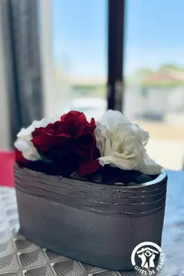 a black container with red and white flowers on a table at La ceriseraie in Trausse