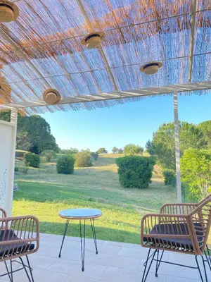 a patio with a table and chairs and a view of a field at Entre Pins et Romarins in Bizanet